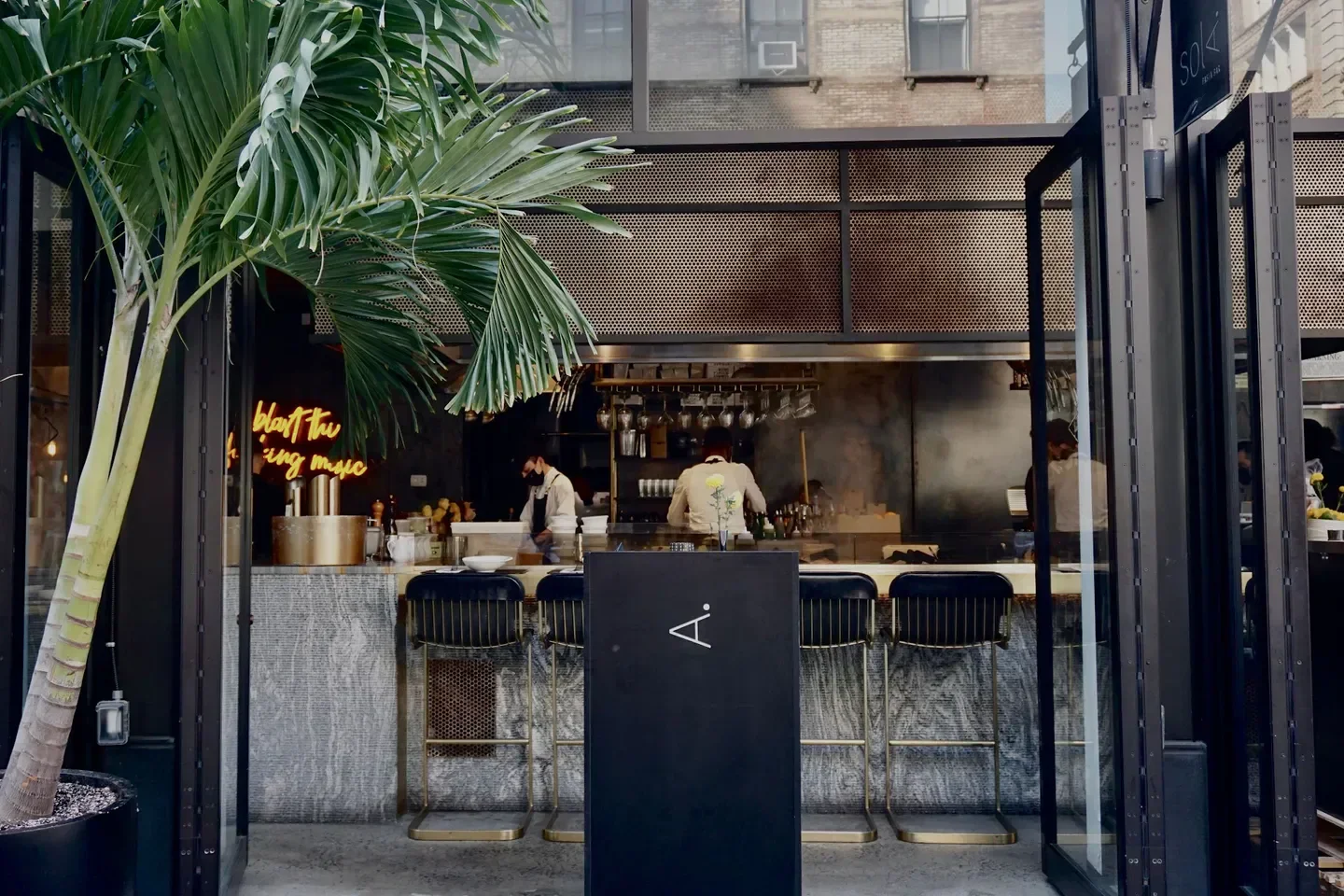 Exterior of A Pasta Bar in New York City with a stylish bar and palm tree.