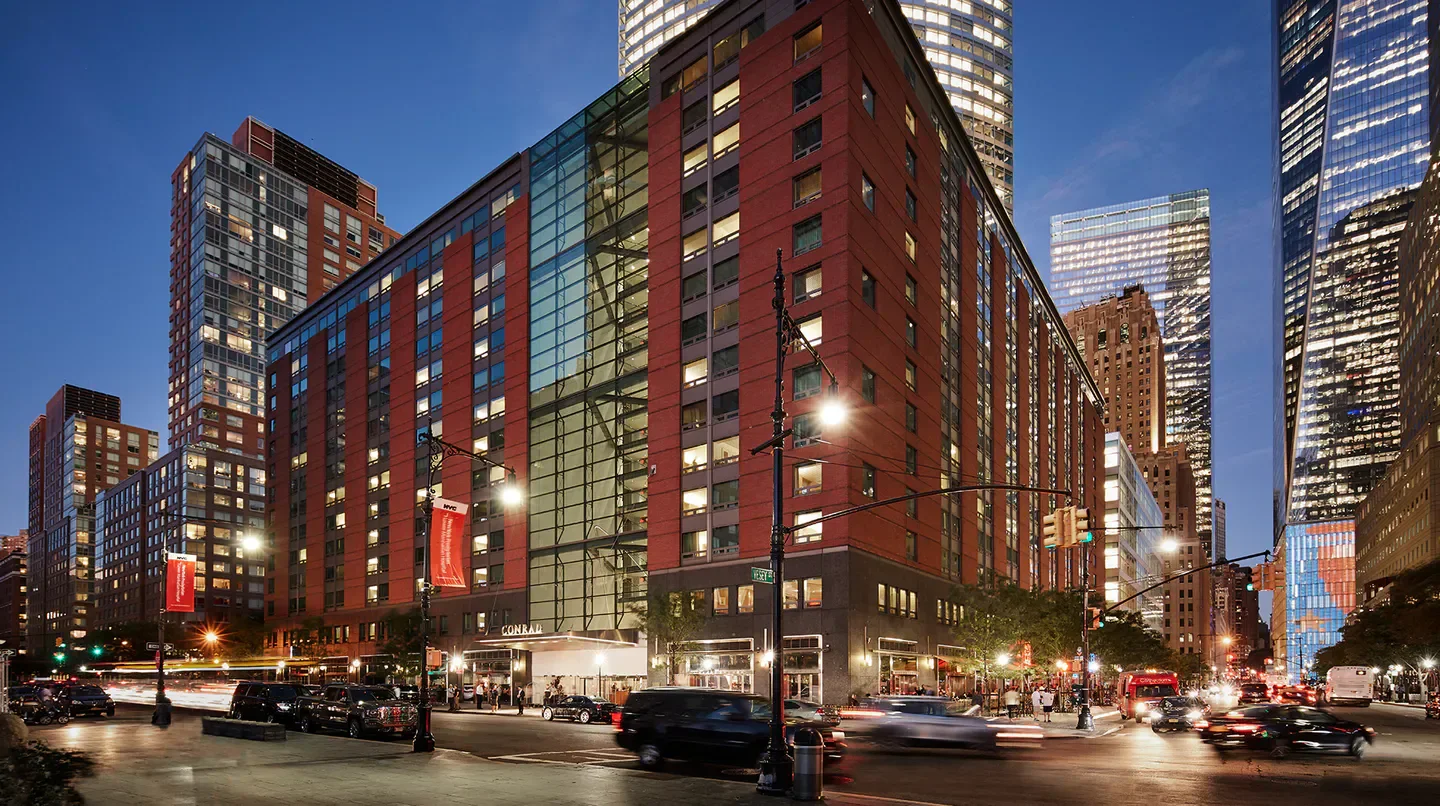 Conrad New York Downtown hotel exterior at dusk in New York City with street lights.