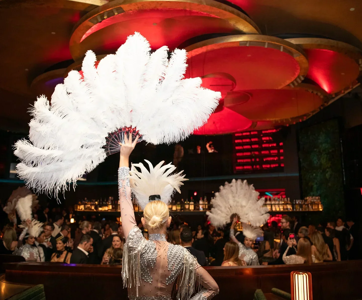 Elegant performer at COTE New York City, holding a feathered fan at the restaurant.
