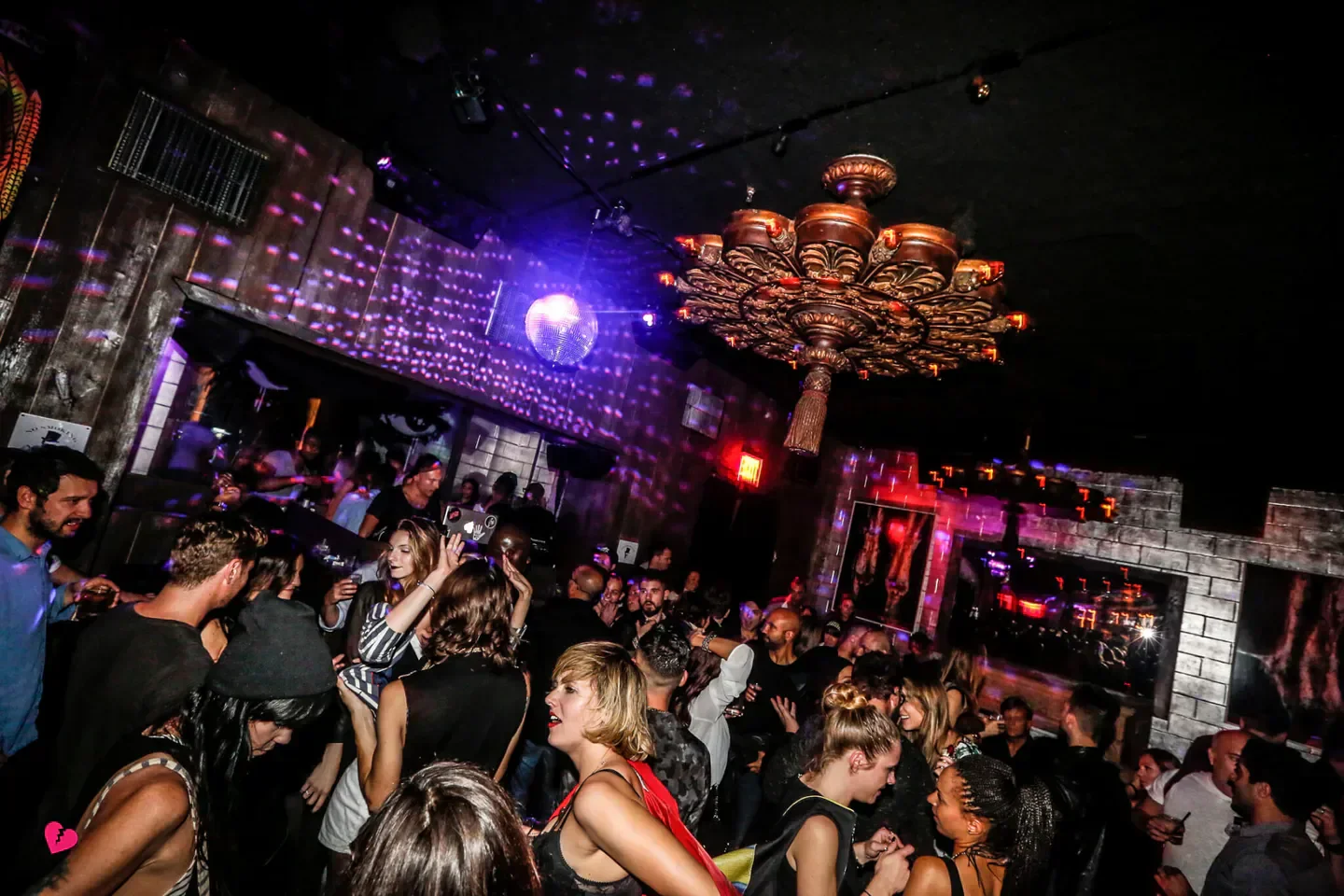 Dancing crowd at Electric Room nightclub in New York City with a disco ball and chandelier