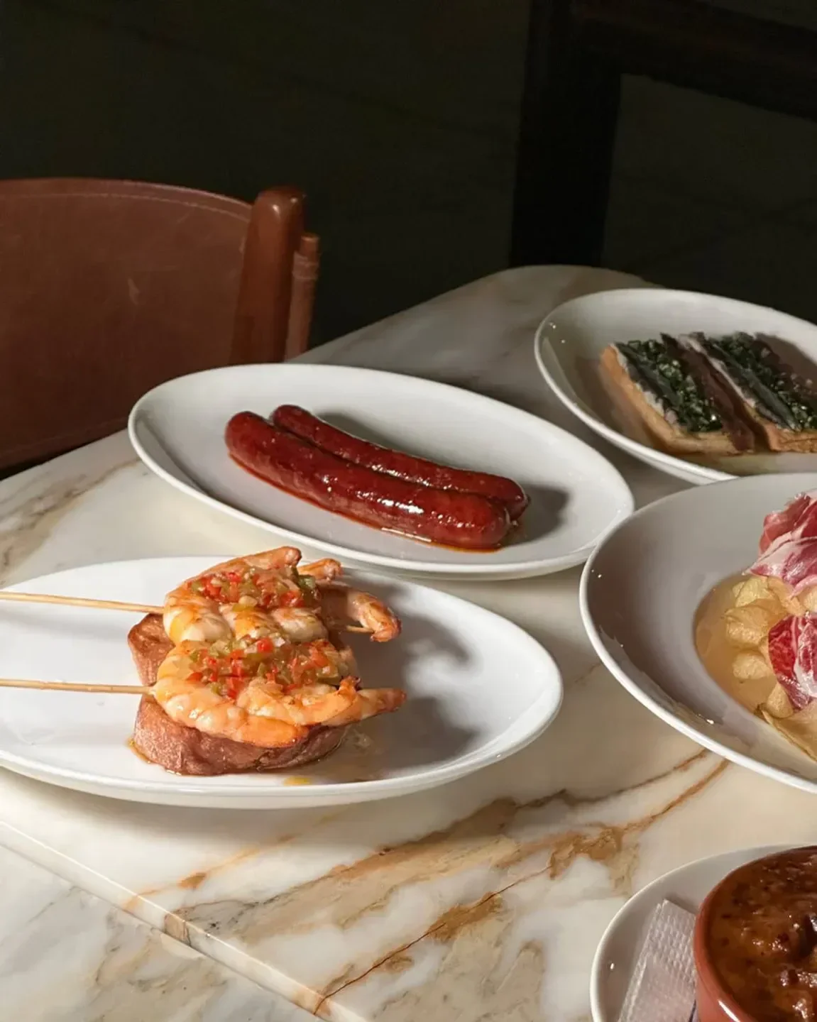 Delicious dishes at Ernesto’s in New York City: shrimp, sausage, and tapas on a marble table.