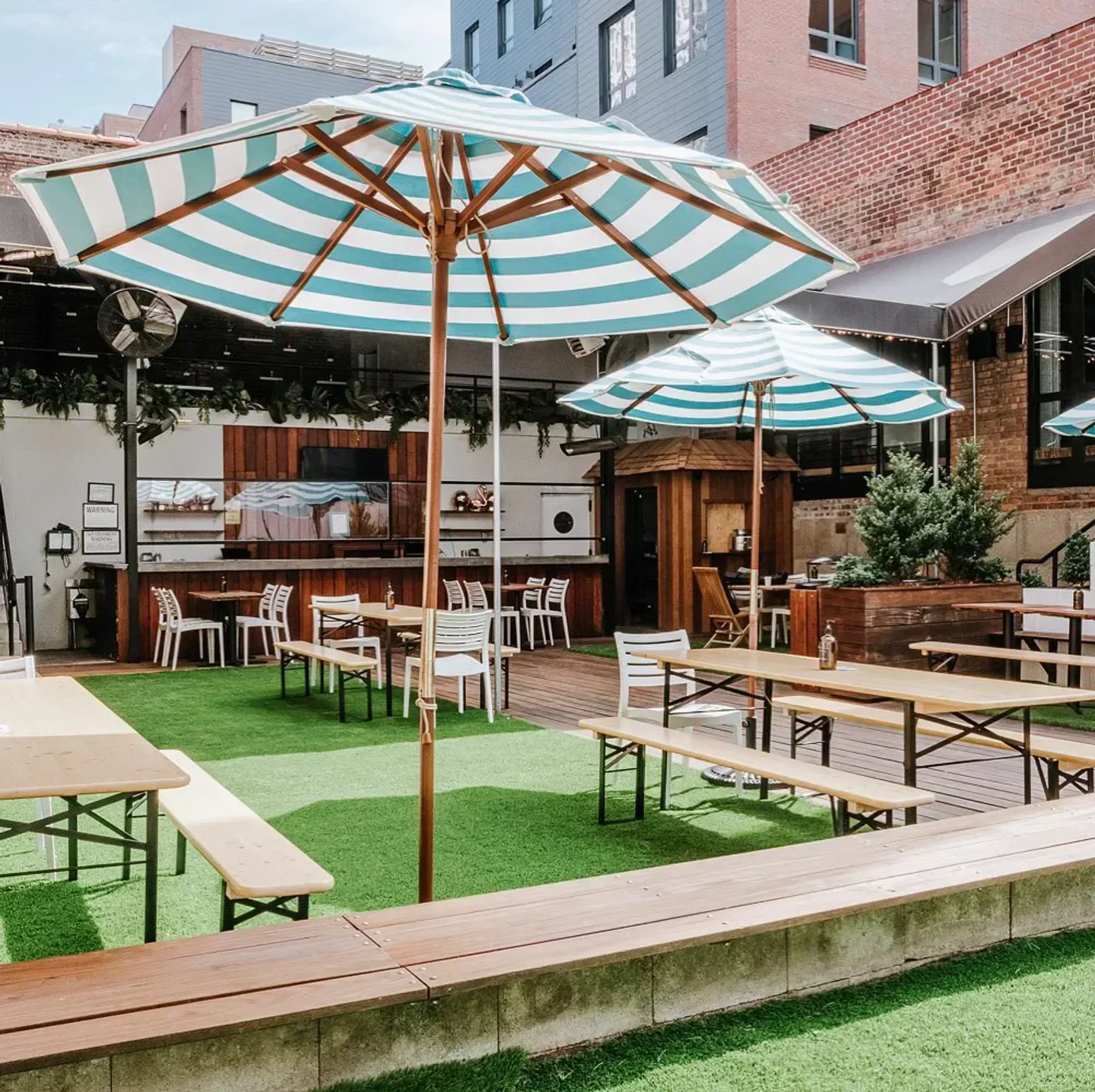 Outdoor seating at FREEHOLD Rooftop in New York City with striped umbrellas