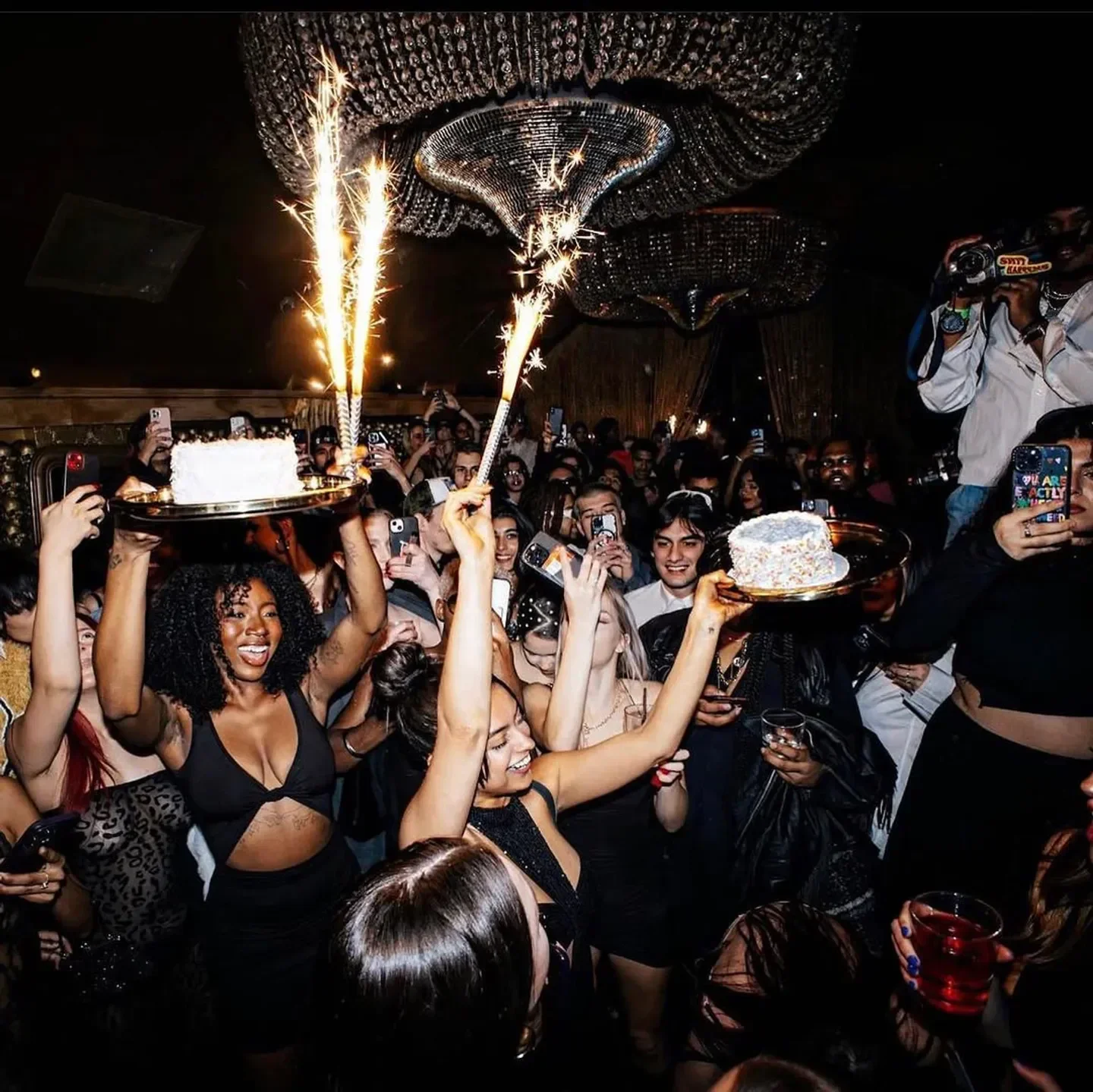 Celebration at Gold Bar in New York City with cake and sparklers, surrounded by people.