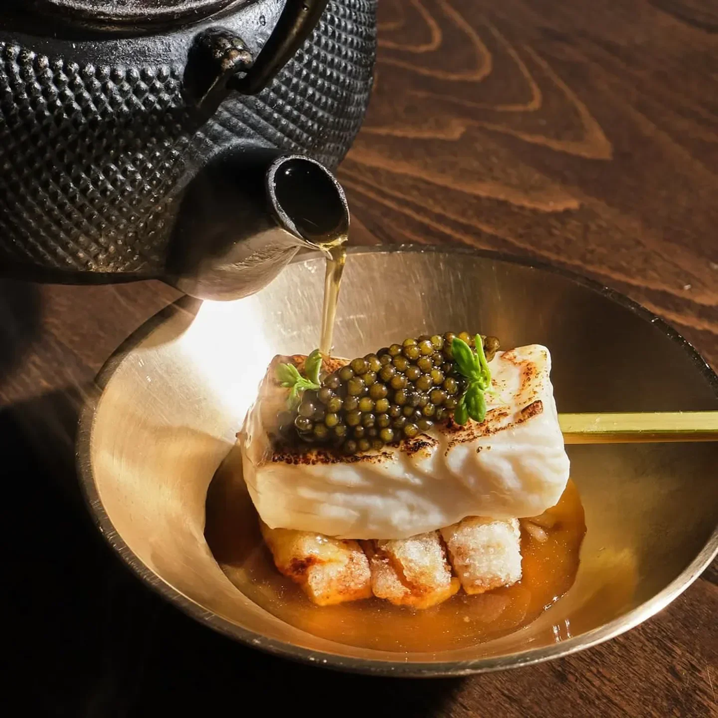 Delectable Kochi New York City dish, caviar-topped fish with sauce, poured from a tea pot
