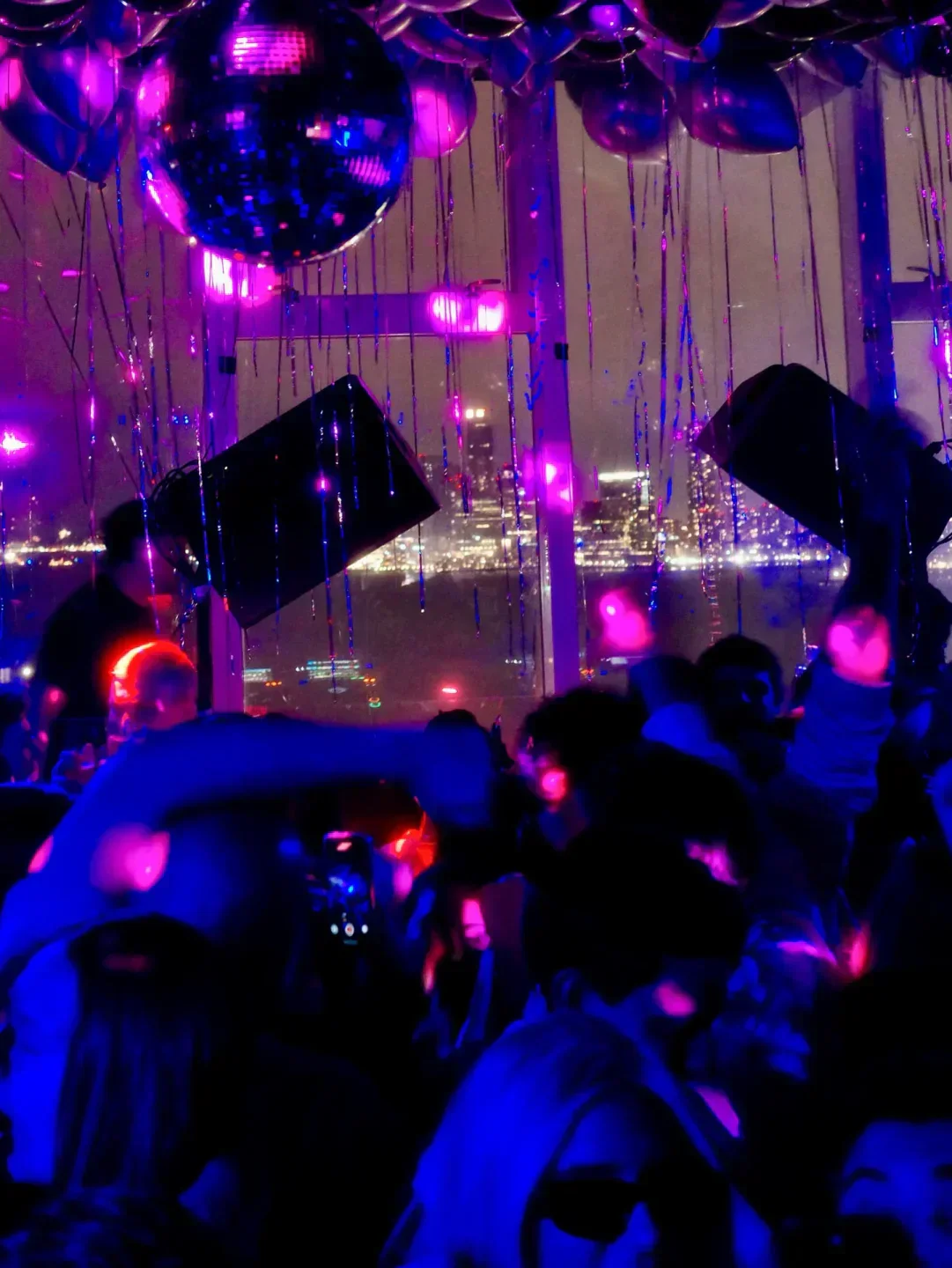 Nightclub scene at Le Bain in New York City with disco ball and city lights.