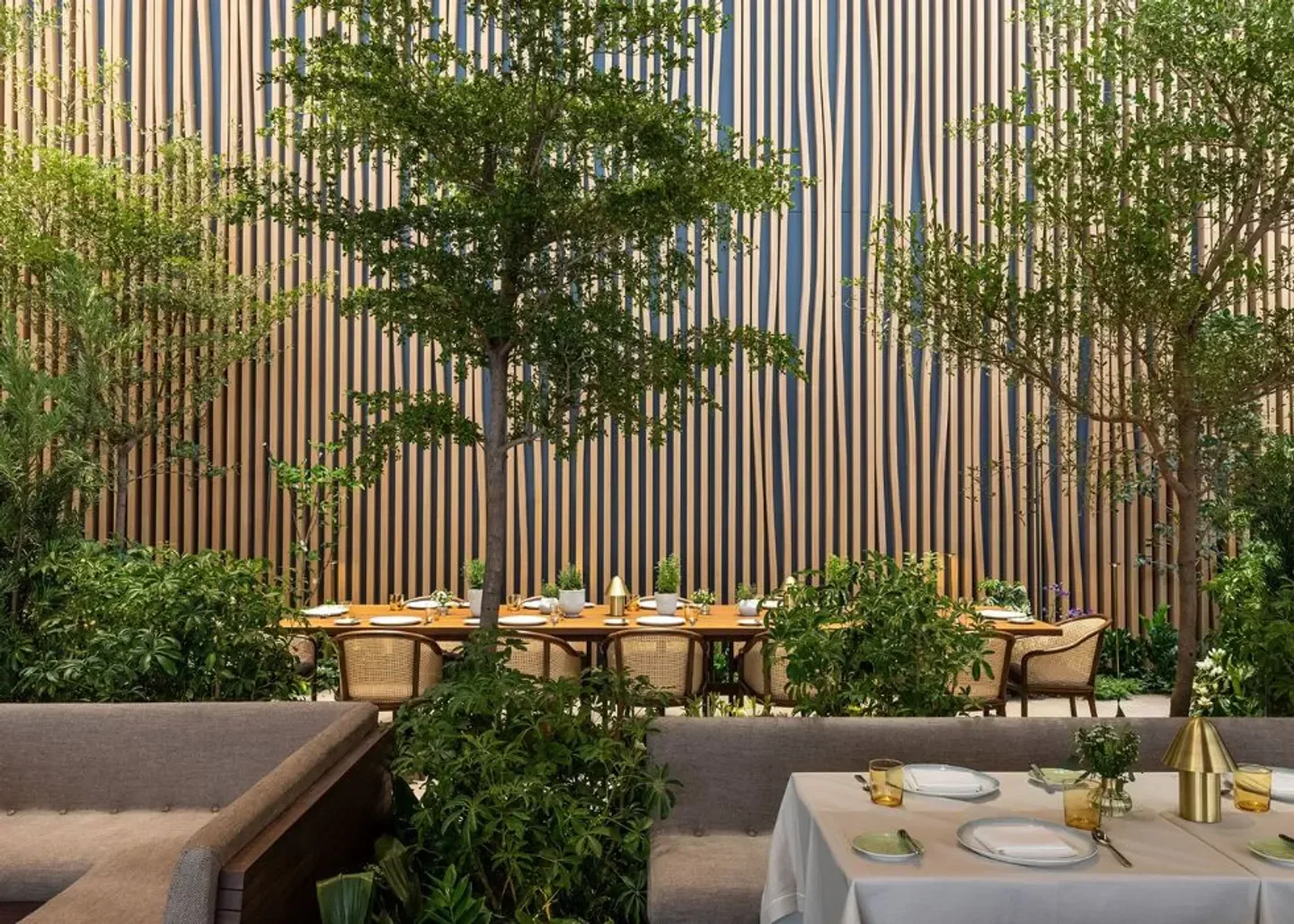 Dining space at Le Pavillon in New York City with wooden decor and lush greenery.