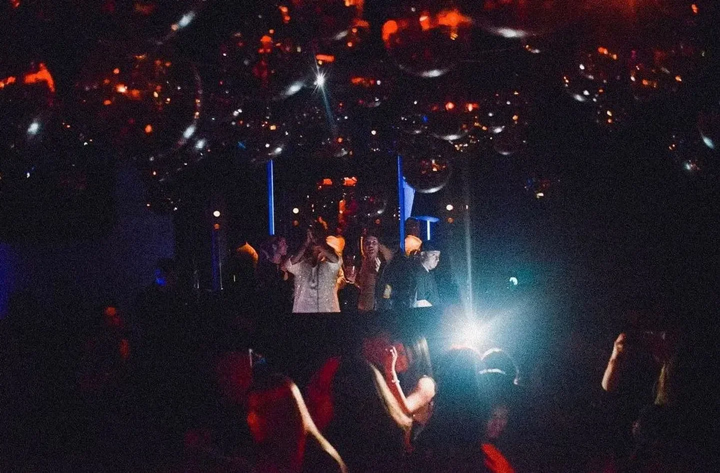 Energetic night at Loosie's Nightclub in New York City with disco ball ceiling and crowd.