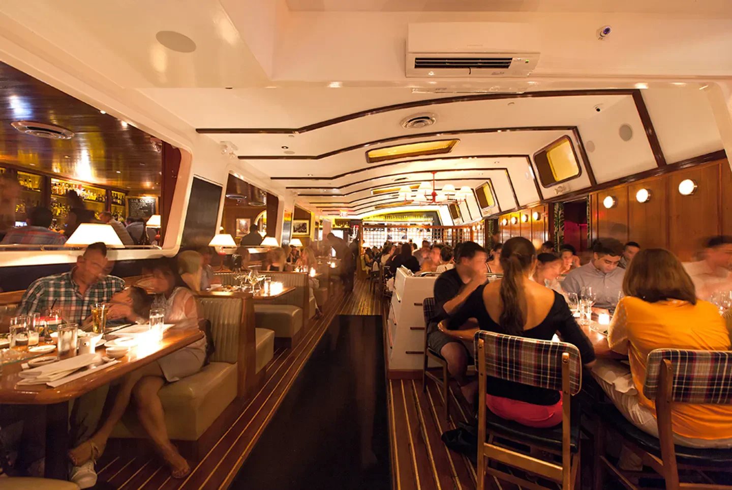 Interior dining at Lure Fishbar in New York City with nautical design and patrons.