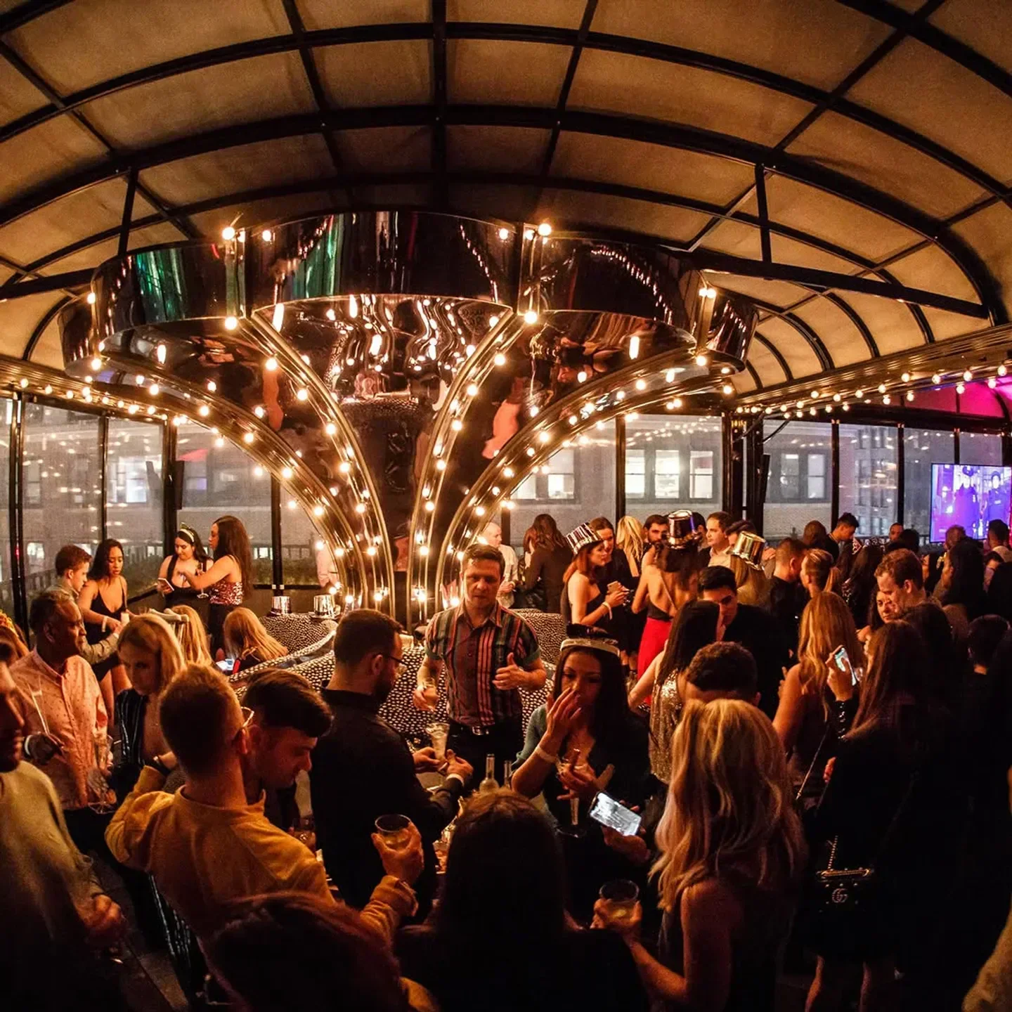 Busy rooftop at Magic Hour Rooftop & Bar in New York City with people celebrating.