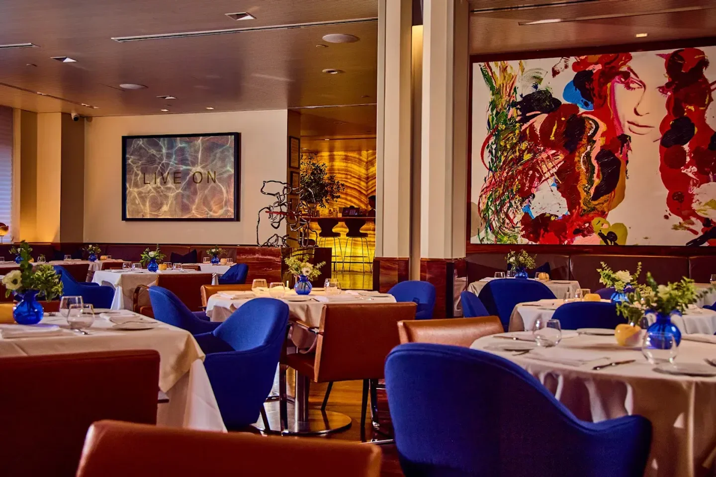 Elegant dining area at Marea restaurant in New York City with blue chairs and art.