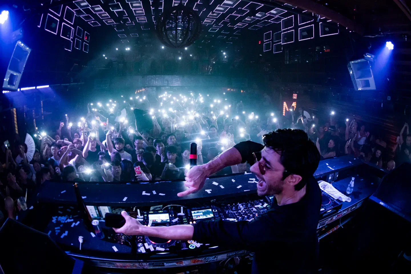 DJ performing at Marquee nightclub in New York City, crowd holding up phones.