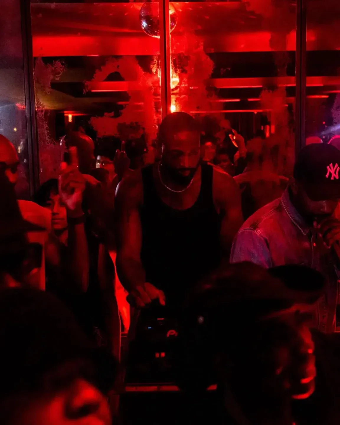 Inside The Blond nightclub in New York City with crowd, red lighting and DJ.
