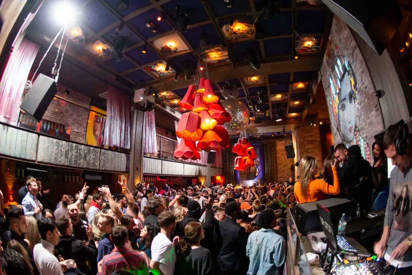 Crowded dance floor at The Box nightclub in New York City with DJs and decor.