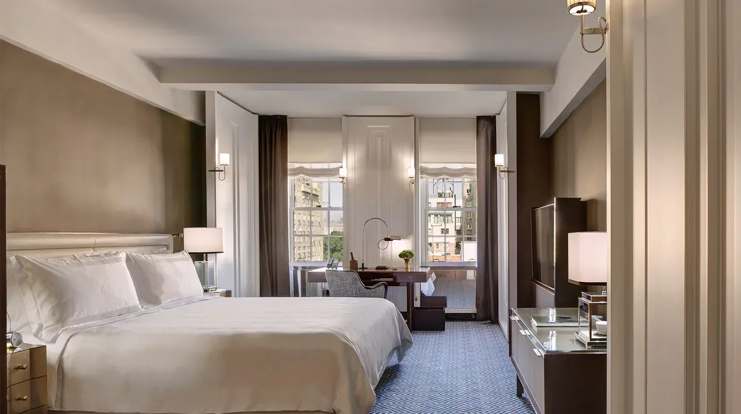 Elegant bedroom at The Carlyle, A Rosewood Hotel, offering views of New York City.
