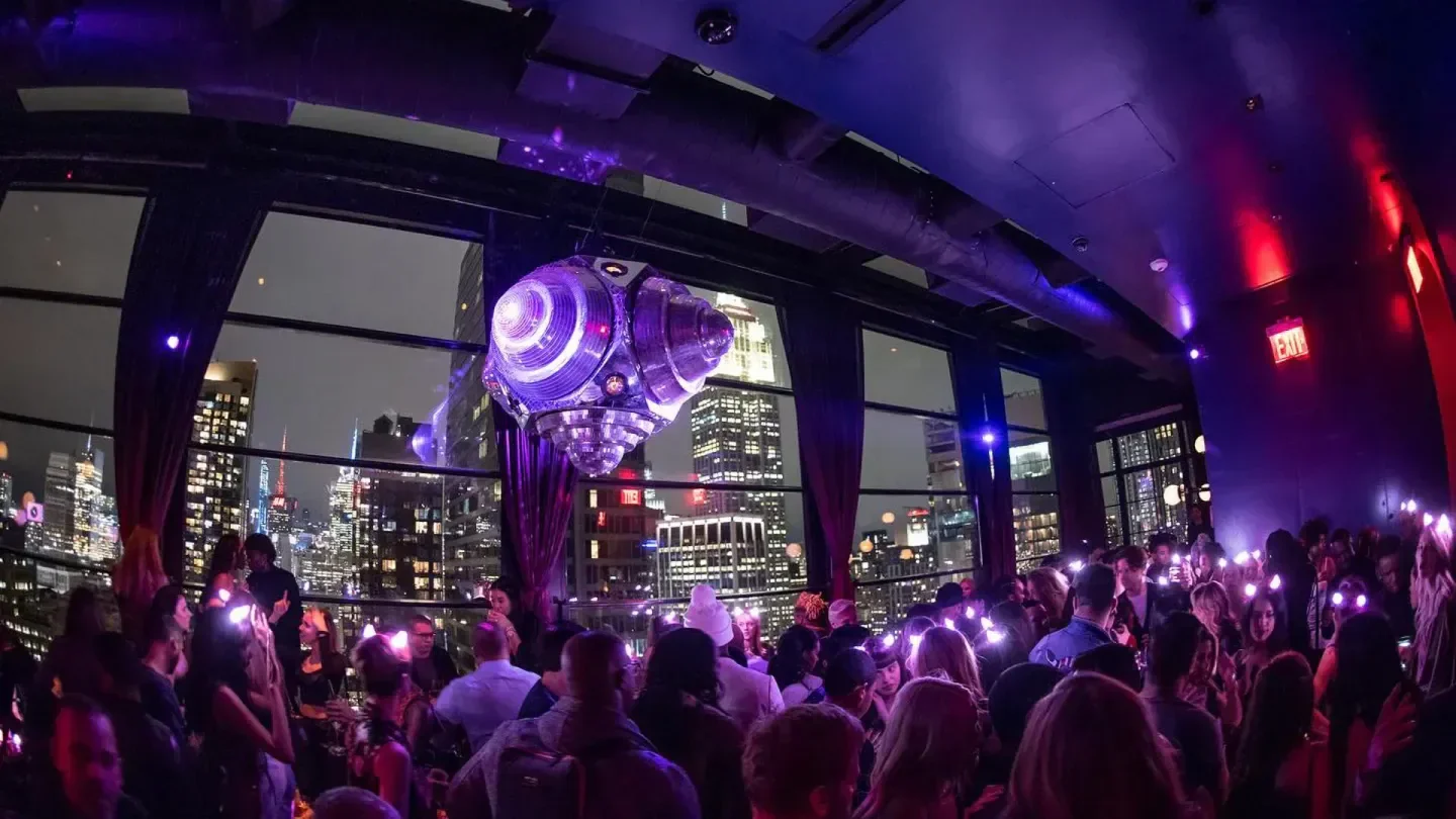 Nightclub scene at The Fleur Room in New York City with city skyline views and lights.