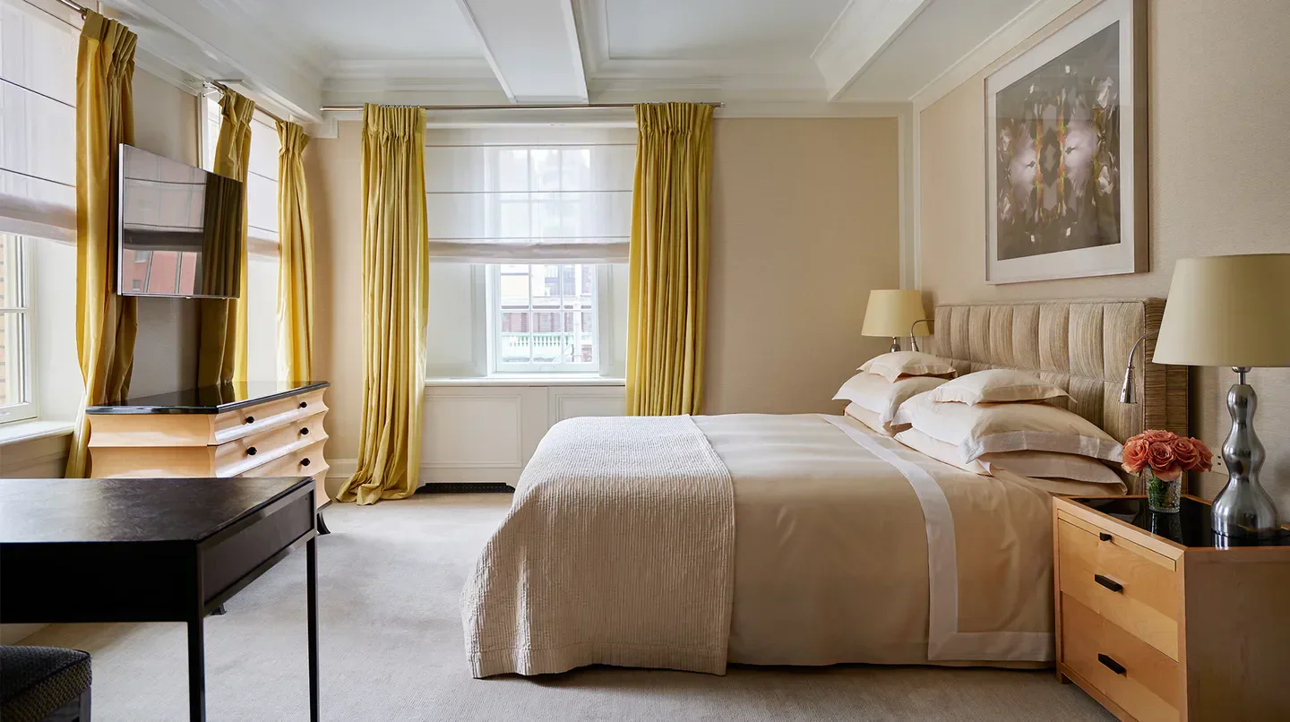 Cozy bedroom at The Mark in New York City with elegant yellow drapes and plush bedding