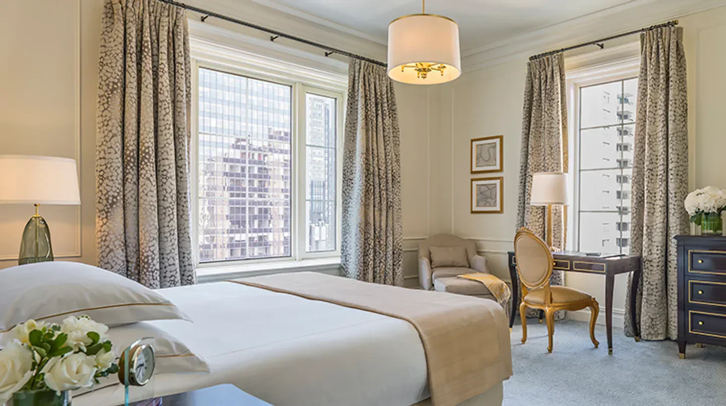 Elegant bedroom at The Plaza Hotel in New York City with city views from the window.